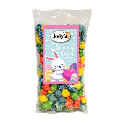 Jody’s Gourmet Popcorn Bunny Corn in a clear bag filled with colorful candy popcorn in pink, blue, and yellow, featuring a label with a smiling bunny and spring eggs.